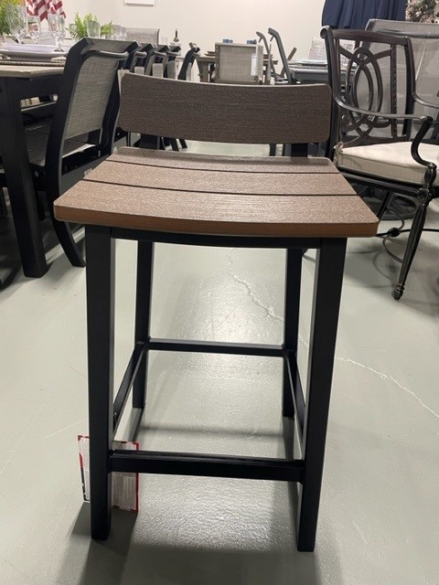 A Bazza brown and black bar stool with a rectangular seat and backrest displayed in a store setting with various other chairs and tables in the background.
