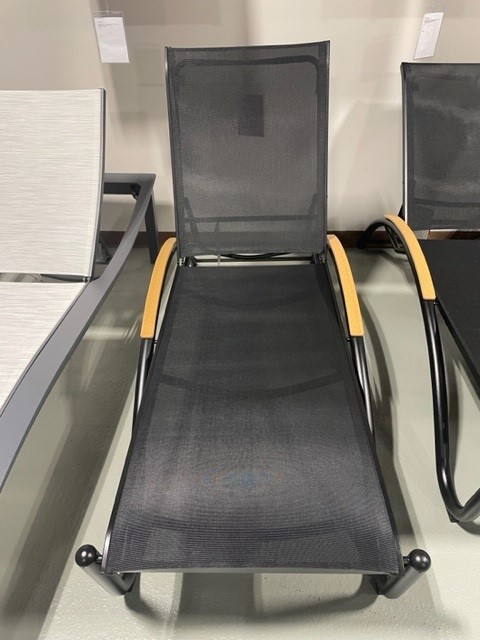 A modern Helios Sling black mesh lounge chair with a lightweight metal frame and wooden armrests, displayed on a gray showroom floor.