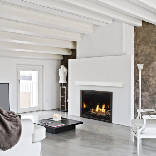 Modern living room with white furniture, a sleek fireplace, exposed beams on the ceiling, and a mix of smooth and textured walls.