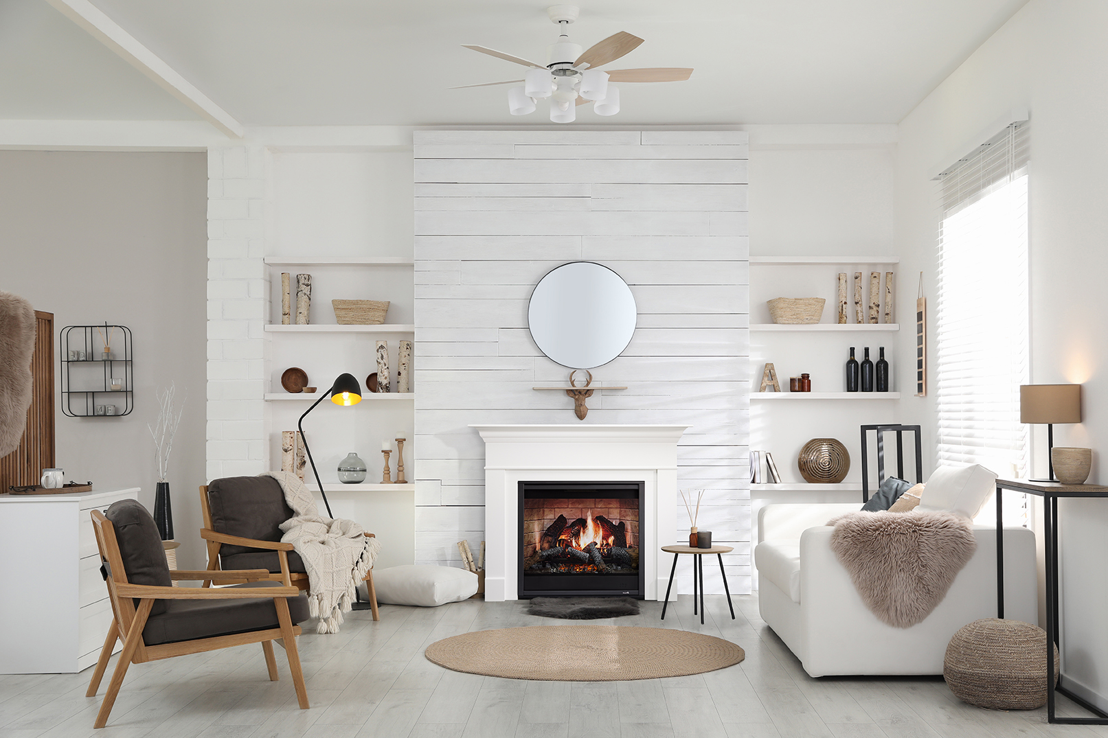 A cozy, modern living room featuring a SimpliFire Inception Electric Fireplace, wooden furniture, a plush sofa, and shelves with decorative items. A circular mirror hangs above the fireplace.