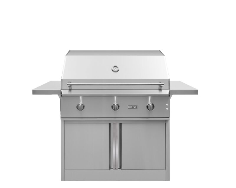 A stainless steel outdoor gas grill with a closed lid, featuring four control knobs on the front and a dual-door storage compartment below, isolated on a white background.