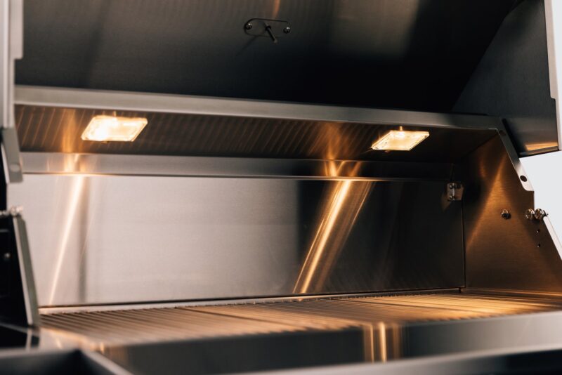 Interior of a modern, clean stainless steel oven with the door open, showcasing its lit interior and racks.
