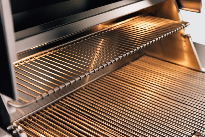 Close-up view of a clean, stainless steel barbecue grill with the lid open, showing shiny grill grates ready for cooking.