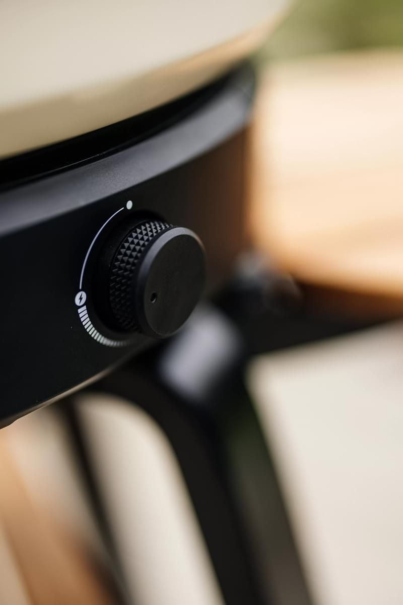 Close-up of a black control knob on a modern appliance with a metal and wood design, showcasing intricate textures and details.