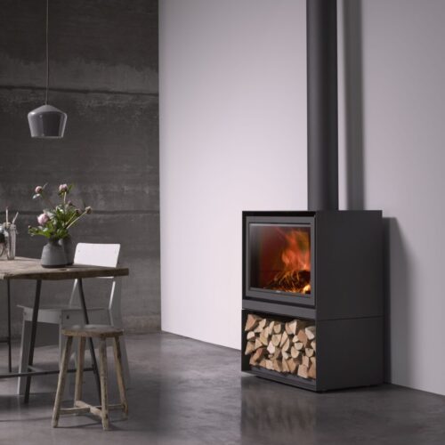 Modern minimalist room with a freestanding black fireplace stocked with wood, next to a small dining area with a wooden table and metal chairs. neutral colors and clean lines dominate the space.