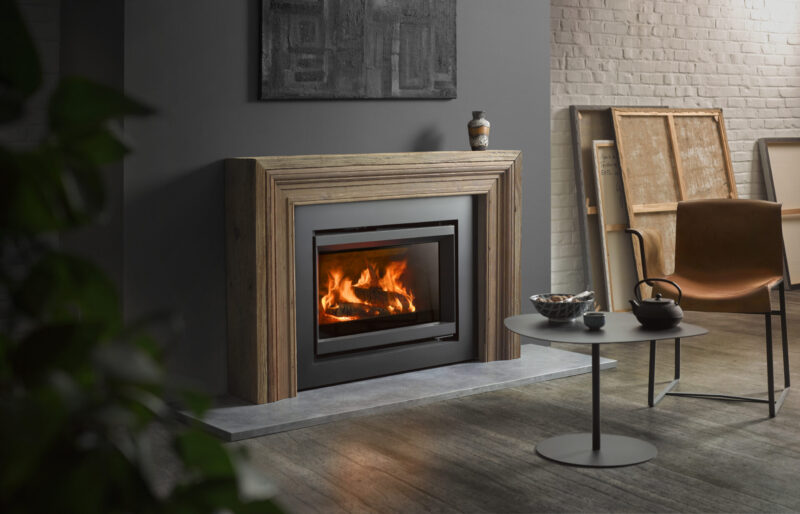 A modern living room featuring a lit fireplace built into a gray stone wall, with stylish chairs, a round table, and minimalist decor.