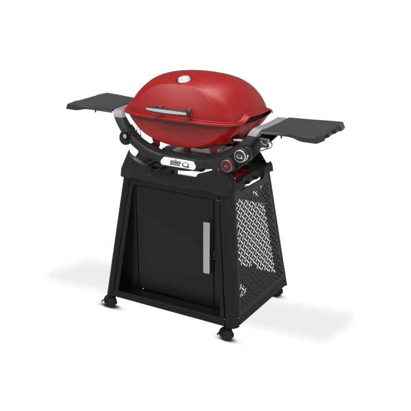 A modern red charcoal grill with a closed lid, mounted on a black cart with side shelves and a cabinet below for storage, isolated on a black background.