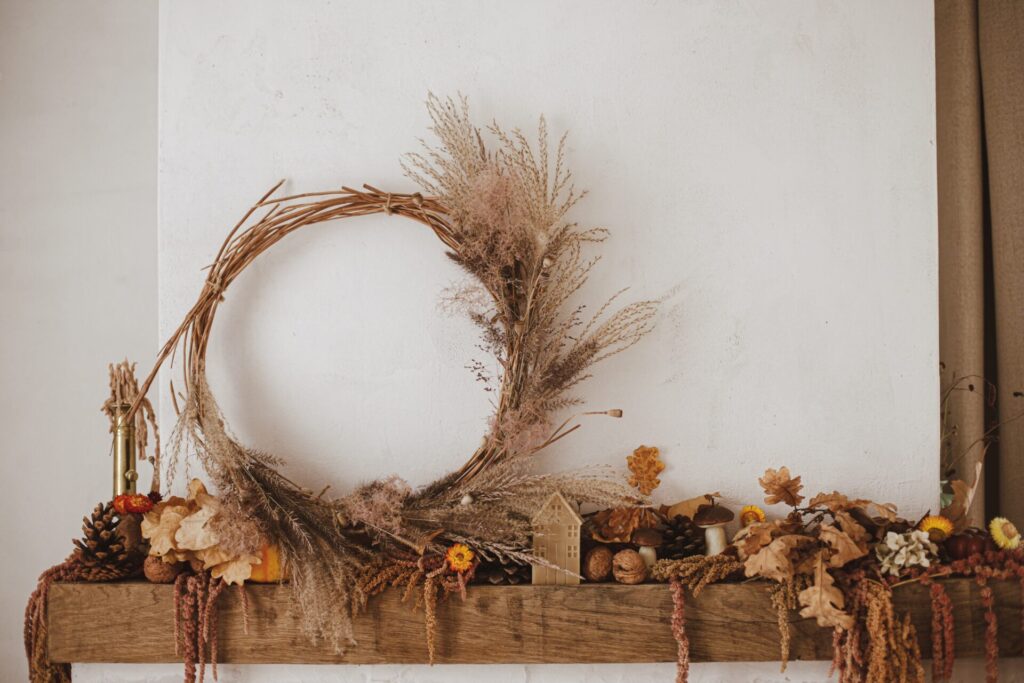 Fall leaves, decorations, and wreath sit on top of a wooden fireplace mantel